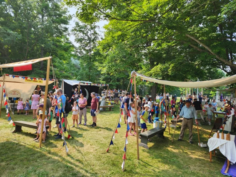 Various text set up with colourful bunting and carnival games are played by crowds of children and their families.